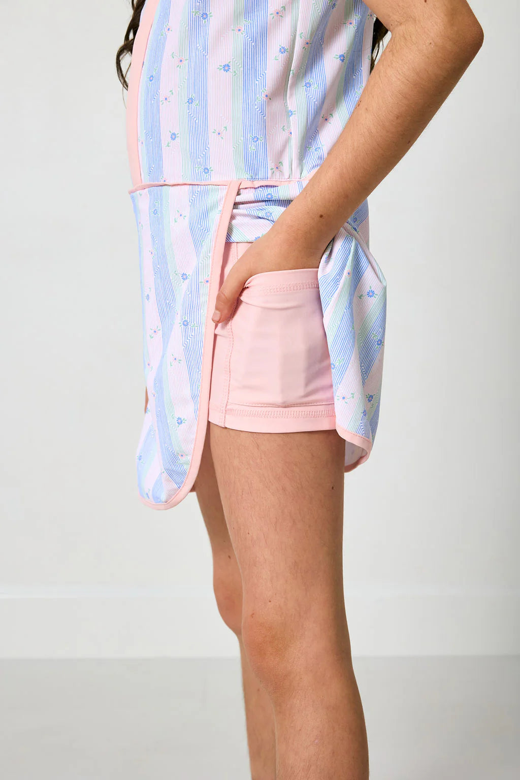 Person wearing a colorful striped shirt and pink shorts on a plain background