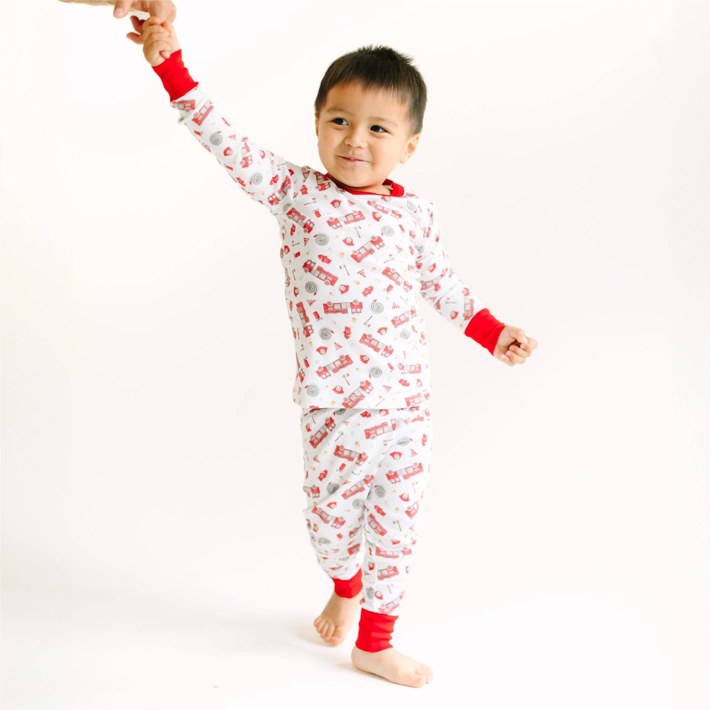 Child wearing a red and white pajama set with car pattern on a white background