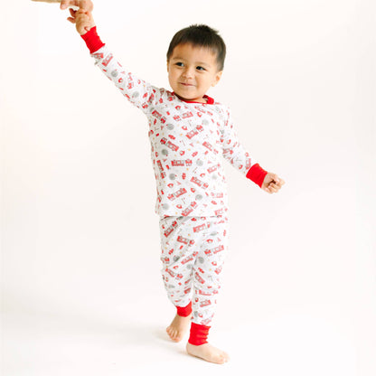 Child wearing a red and white pajama set with car pattern on a white background