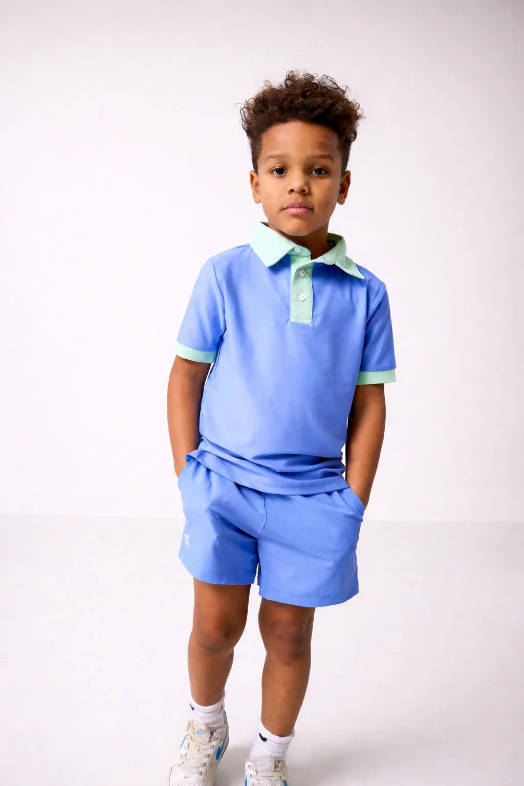 Child wearing a blue polo shirt and shorts set on a white background