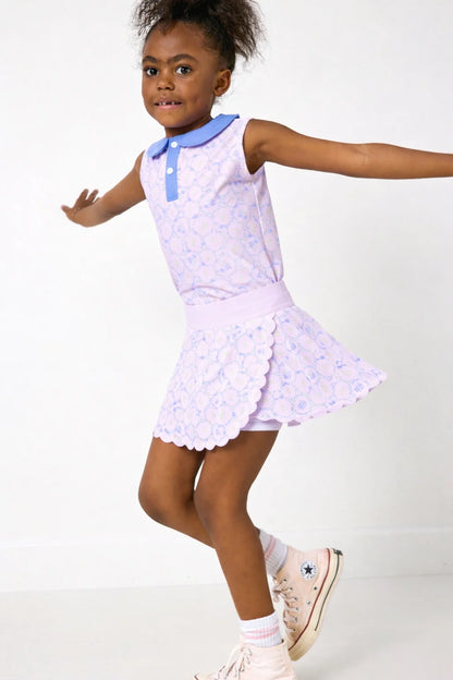 Young girl wearing a light purple dress with blue trim on a white background