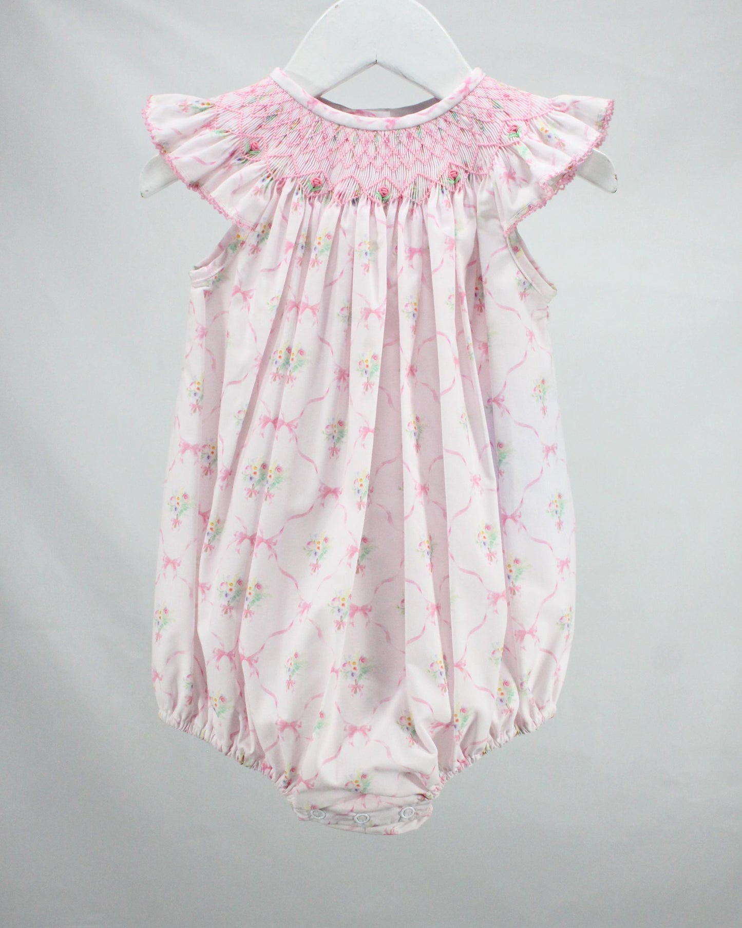 Pink floral baby romper on a gray background