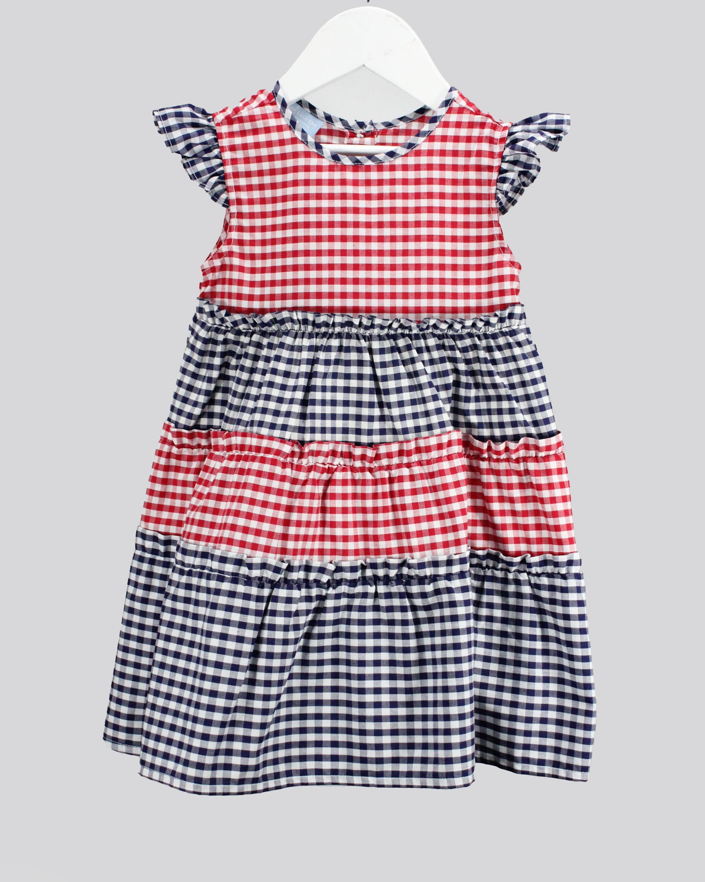 Red and blue checkered dress on a white hanger against a gray background