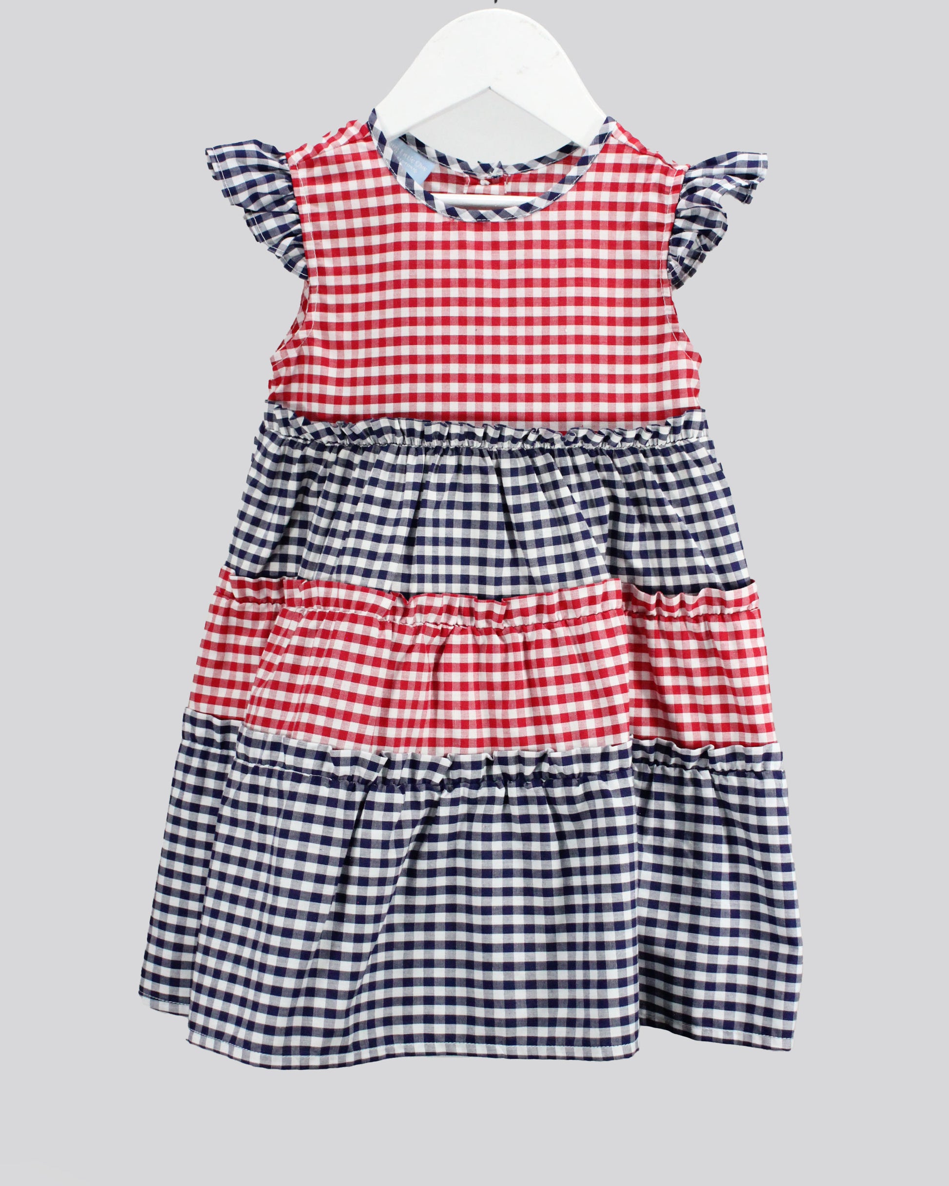 Red and blue checkered dress on a white hanger against a gray background