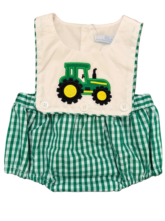 Green and white checkered romper with a John Deere tractor design on a wooden surface