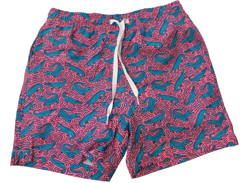 Pair of swim shorts with pink and blue pattern on a beige surface