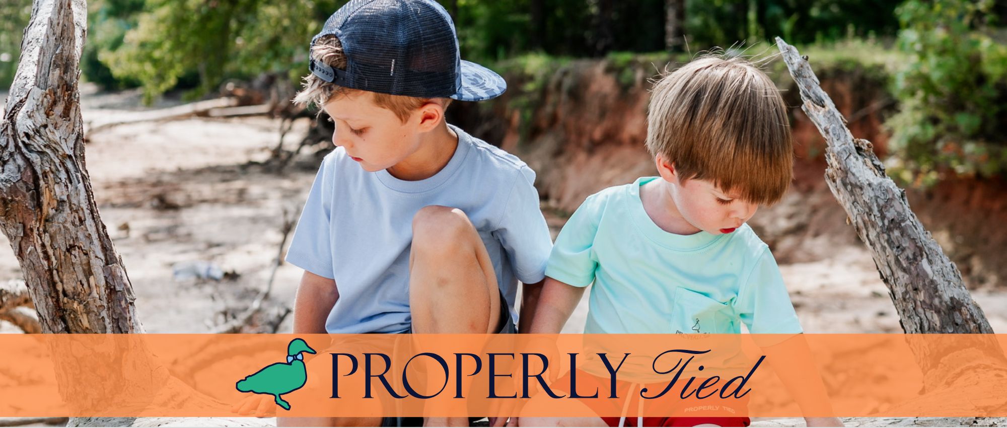 Two boys sitting outside with the Properly Tied Branding.