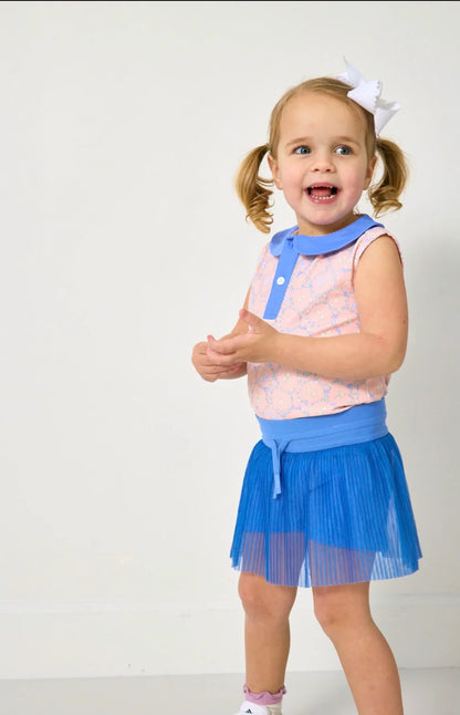 Young girl wearing a pink top with a blue collar and blue skirt on a white background
