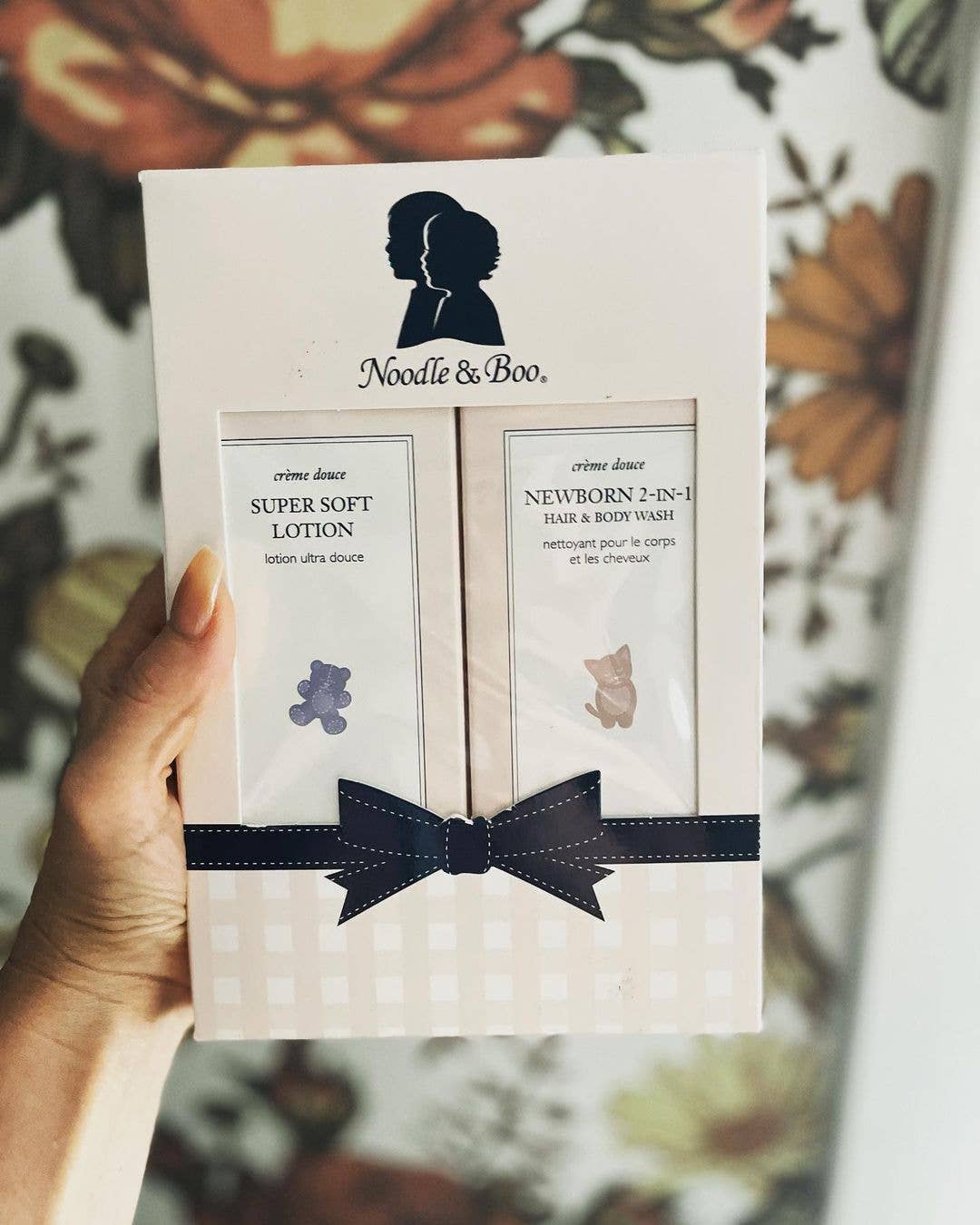 Product packaging with 'Noodle & Boo' branding featuring two baby care items on a floral background.