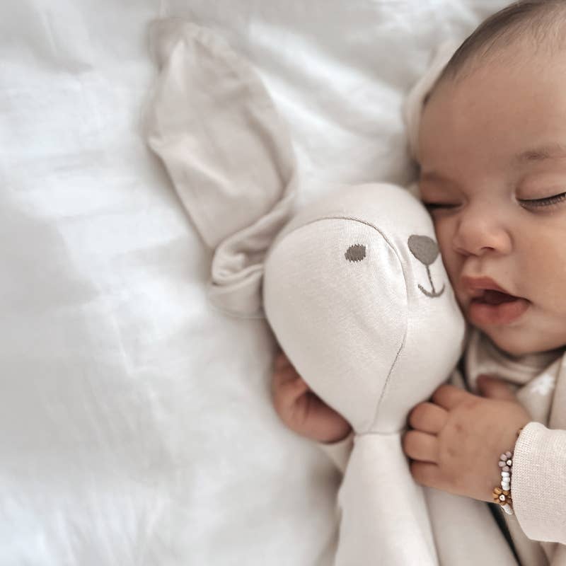 Baby holding a plush toy with a soft white background