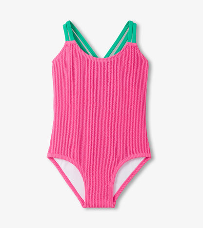 Pink ribbed swimsuit with green straps on a white background